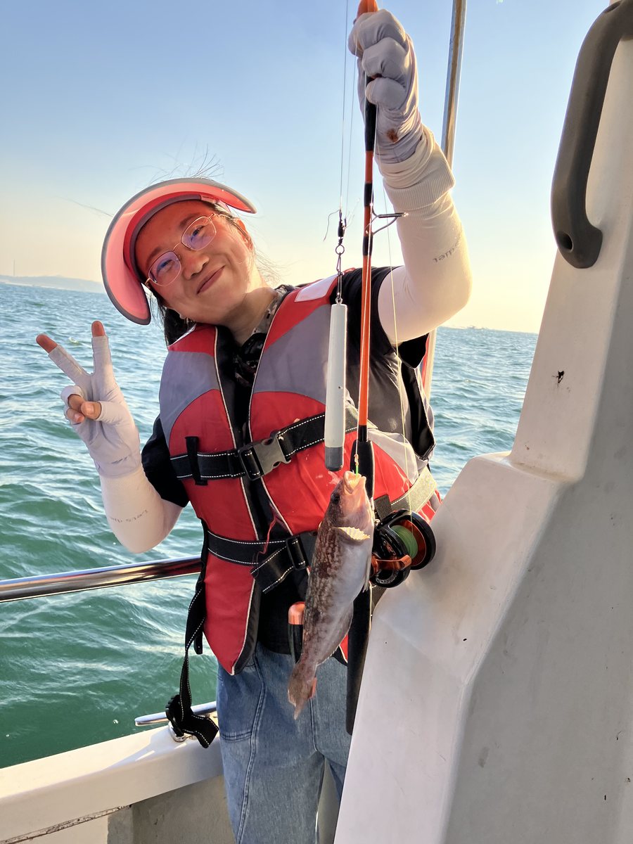 A team member posing with a black fish and holding up two fingers